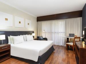 een hotelkamer met een groot bed en een bureau bij Mercure Sao Paulo Grand Plaza Paulista in Sao Paulo