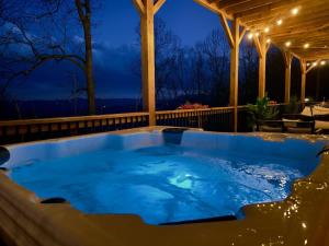 a hot tub on a patio at night at LUXE, Breathtaking Mountain Views, Hot Tub, Fire Pit, Fire Pit Table, Pool Table, 2 Living rooms, Universal EV Station in Hendersonville