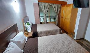 a hotel room with two beds and a television at Hotel Johanan in Valle de Bravo