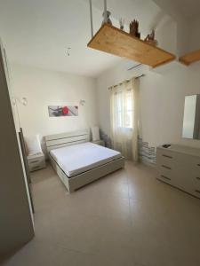 a white bedroom with a bed and a dresser at Casa Relax in Simaxis