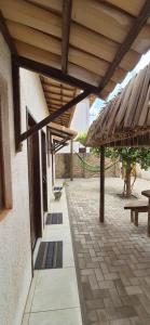 an outdoor patio with a wooden roof and a bench at Pousada Coró in São Miguel do Gostoso