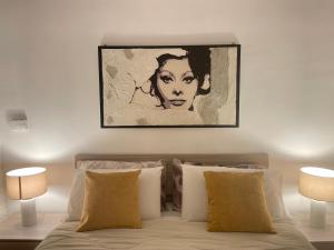 a painting of a woman above a bed with pillows at B&B Le due sorelle in Telese