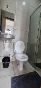 a bathroom with a toilet and a glass shower at Pousada Coró in São Miguel do Gostoso