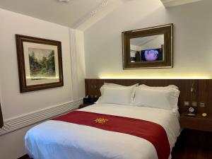 a bedroom with a large bed with two pictures on the wall at Hotel Boutique Casón De Los López in Toledo +153 photos