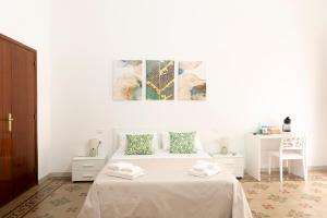 a white bedroom with a white bed with green pillows at B&B Gaudio in San Marco Argentano