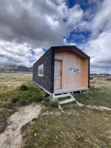 a small shack in a field with a cloudy sky at Tiny House Camino 3 in Puerto Natales