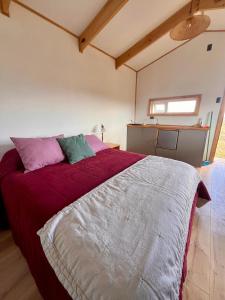 a bedroom with a large bed with red sheets at Tiny House Camino 3 in Puerto Natales