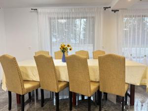 a dining room table with chairs and a vase of flowers at Casa Florina in Predeluţ