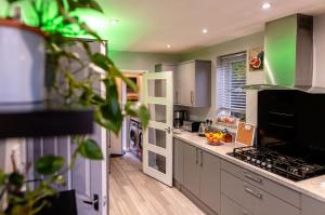 a kitchen with white cabinets and green walls at Sleeps 5 - Free Parking - Near Airport & City in Wythenshawe