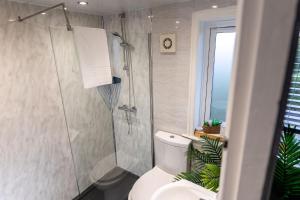 a bathroom with a toilet and a glass shower at Sleeps 5 - Free Parking - Near Airport & City in Wythenshawe +40 photos