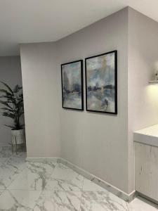three paintings on a white wall with a marble floor at Downtown pearl Amman in Amman