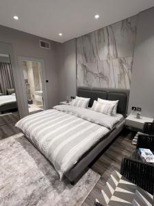 a large bed in a bedroom with a marble wall at Downtown pearl Amman in Amman