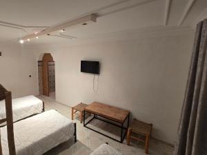 ein Zimmer mit einem Bett, einem Tisch und einem Fernseher in der Unterkunft mouja taghazout in Taghazout