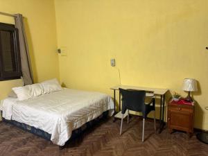 ein Schlafzimmer mit einem Bett, einem Schreibtisch und einem Tisch in der Unterkunft Lodecampu in Asunción