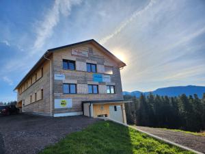 un edificio en una colina con el sol en el cielo en Blickfang Bregenzerwald, en Langenegg