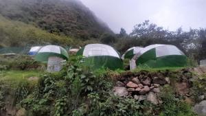 un groupe de tentes vertes et blanches sur une colline dans l'établissement Chaullay Star Domes, à Colcapampa