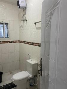 Un baño blanco con inodoro y ducha. en Tracer Wave Cabin, en Akwanga