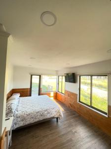 Un dormitorio con una cama y algunas ventanas en Casa Pradera, en Frutillar