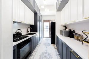 Una cocina con gabinetes blancos y electrodomésticos negros. en BOULEVARD rentals, en Tashkent