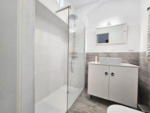 a white bathroom with a shower and a sink at Casa Tradicional in Évora