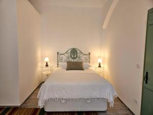 a bedroom with a large white bed with two lamps at Casa Tradicional in Évora