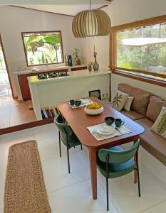 a kitchen and living room with a wooden table and chairs at Casa Positano-Chalé em medio à natureza-Pipa in Pipa