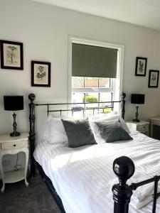 a bedroom with a bed with white sheets and a window at Lavender Cottage, Welton in Welton