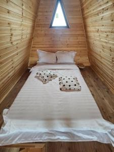 a bed in a wooden cabin with a window at A Frame la Iaz in Mărăcineni +2 photos