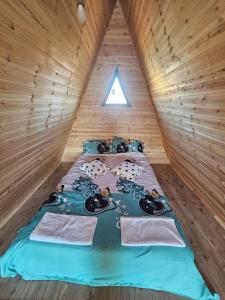 a bed in a wooden cabin with towels on it at A Frame la Iaz in Mărăcineni