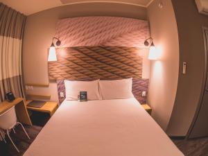 a bedroom with a large bed with a large headboard at ibis Carlos Barbosa in Carlos Barbosa