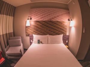 a hotel room with a bed and a chair at ibis Carlos Barbosa in Carlos Barbosa +71 photos