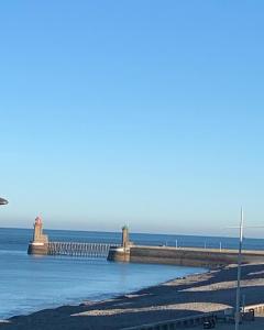 a pier on the beach with the ocean in the background at Gîte Les pieds dans l eau à Fécamp avec pleine vue mer in Fécamp