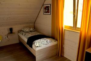 a small bed in a room with a window at Dom Między Wzgórzami in Tylicz
