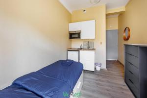 Una pequeña habitación con una cama y una cocina. en COMM - Proudhon 5 - SC - Studio bien équipé à Besançon, en Besançon 2 fotos más