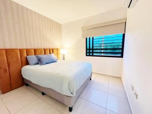 a bedroom with a large bed with a window at Departamento Moderno Azul Cielo - 2 Albercas - 3 Min Malecón y Playas in Mazatlán +11 photos