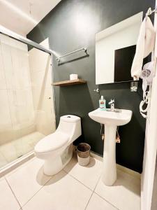 a bathroom with a white toilet and a sink at Departamento Moderno Azul Cielo - 2 Albercas - 3 Min Malecón y Playas in Mazatlán