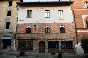 an old brick building with a white facade at Domus Acaja in Pinerolo