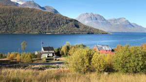 a house next to a body of water with mountains at Myrvoll trails og view in Lakselvbukt