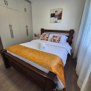 a bedroom with a large bed with a brown blanket at Golden Mango Heights - Urban Family Suite - One Bedroom Apartment - Restaurant, Workspace, City Views, Fast WiFi, Sauna, Fitness Facilities, Secure Parking And Kids Play Area in Nairobi