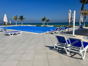 a group of lounge chairs and a swimming pool at Beiruty House -Elegant Family Seaside Villa in As Sīfah