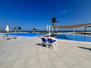 a group of chairs sitting next to a swimming pool at Beiruty House -Elegant Family Seaside Villa in As Sīfah