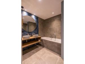 a bathroom with two sinks and a tub and a mirror at Modern villa in De Cocksdorp near the beach in De Cocksdorp