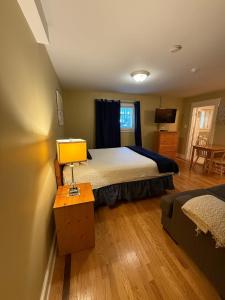 een slaapkamer met een bed en een tafel met een lamp bij Cozy Manor Studio Parking WiFi in St. John's
