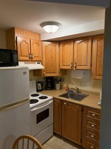 a kitchen with wooden cabinets and a white stove top oven at Midstream Manor Unit 1 - Studio in St. John's