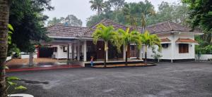 a house with palm trees in front of it at Chakos Homestay in Kaduturutti