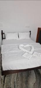 a white bed with two white towels on it at Chakos Homestay in Kaduturutti
