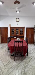 a dining room with a table and a clock on the wall at Chakos Homestay in Kaduturutti