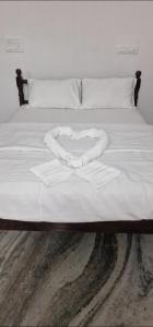 a white bed with a heart shapedvisor on it at Chakos Homestay in Kaduturutti