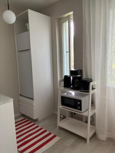 a living room with a microwave and a kitchen with a window at Cozy apartment for 2 - free parking in Oulu