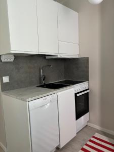 a kitchen with white cabinets and a sink at Cozy apartment for 2 - free parking in Oulu +1 photo